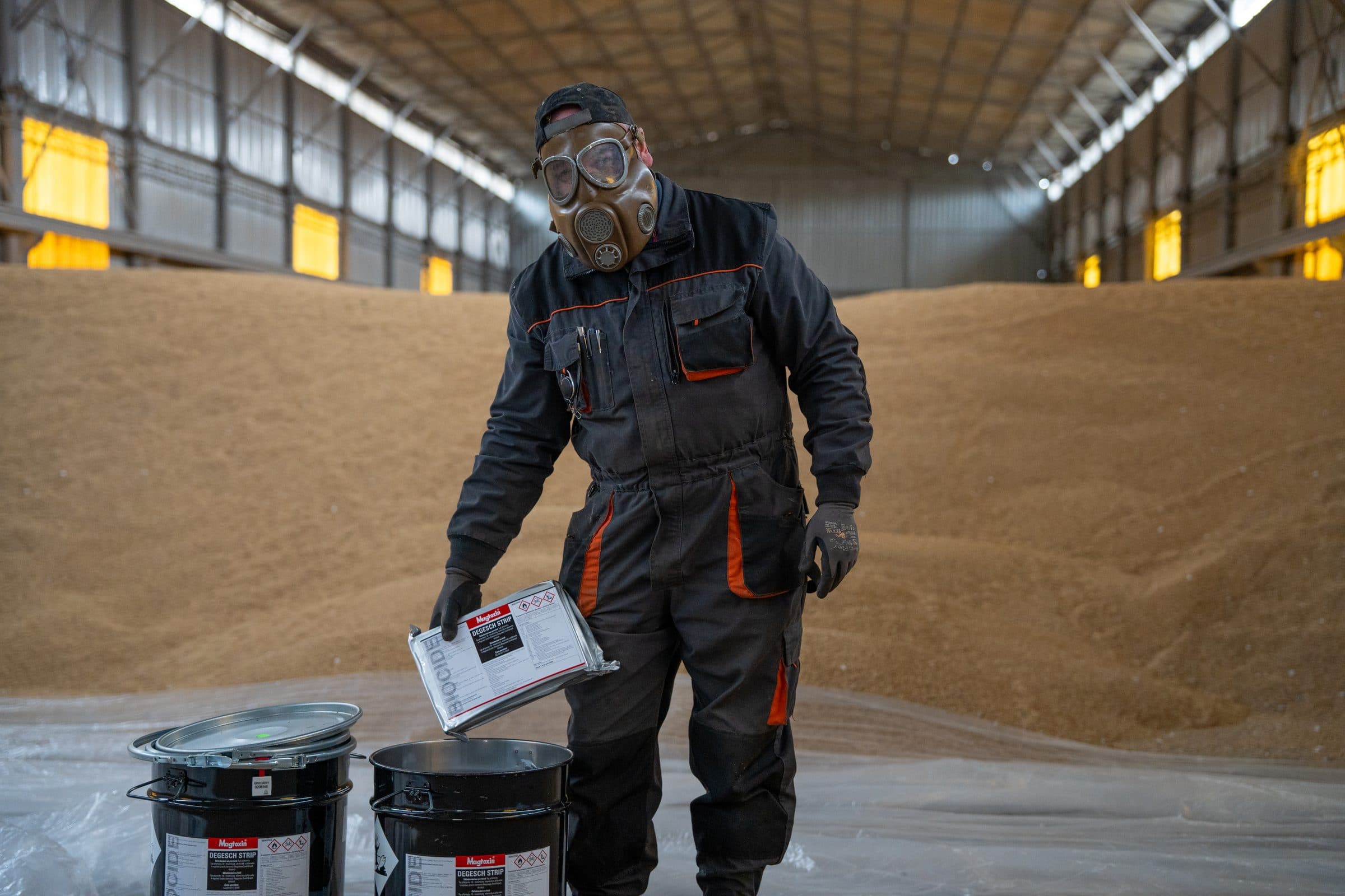 Technik v ochranné masce s přípravkem k plynování ve skladu obilí